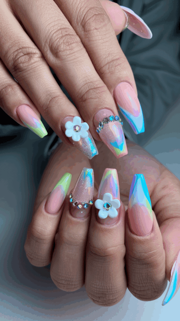 A set of colorful acrylic nails featuring a gradient of pastel shades with holographic effects, adorned with rhinestones and 3D floral decorations.