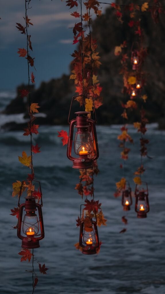 Hanging lanterns adorned with autumn leaves, illuminated against an ocean backdrop at dusk, creating a warm and cozy atmosphere.